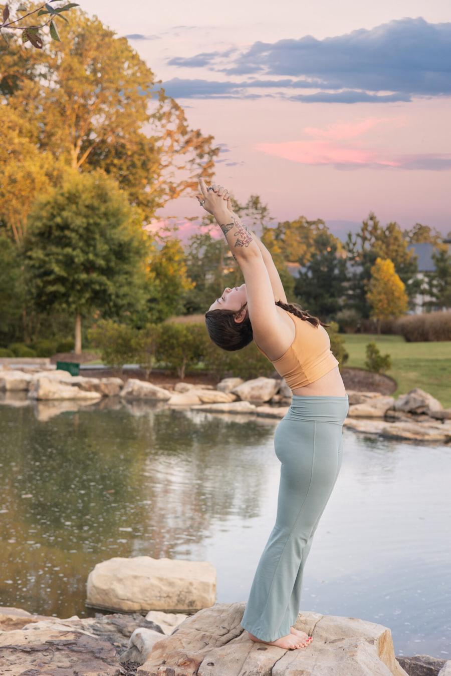 Personal branding session at golden hour — woman stretching on a rock beside a pond