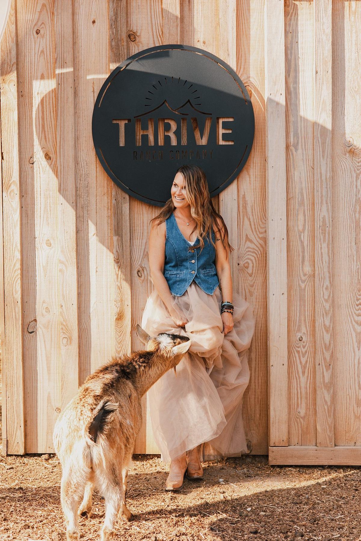 Personal branding photo of a farm owner laughing as a goat nibbles her tulle skirt