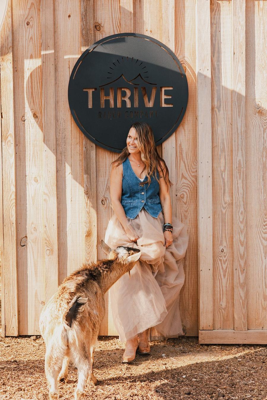 Personal branding photo of a farm owner laughing as a goat nibbles her tulle skirt