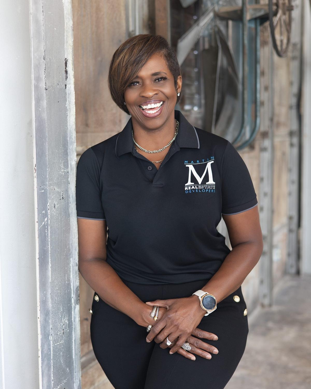 Personal branding portrait of a real estate developer in a branded black polo by a barn door