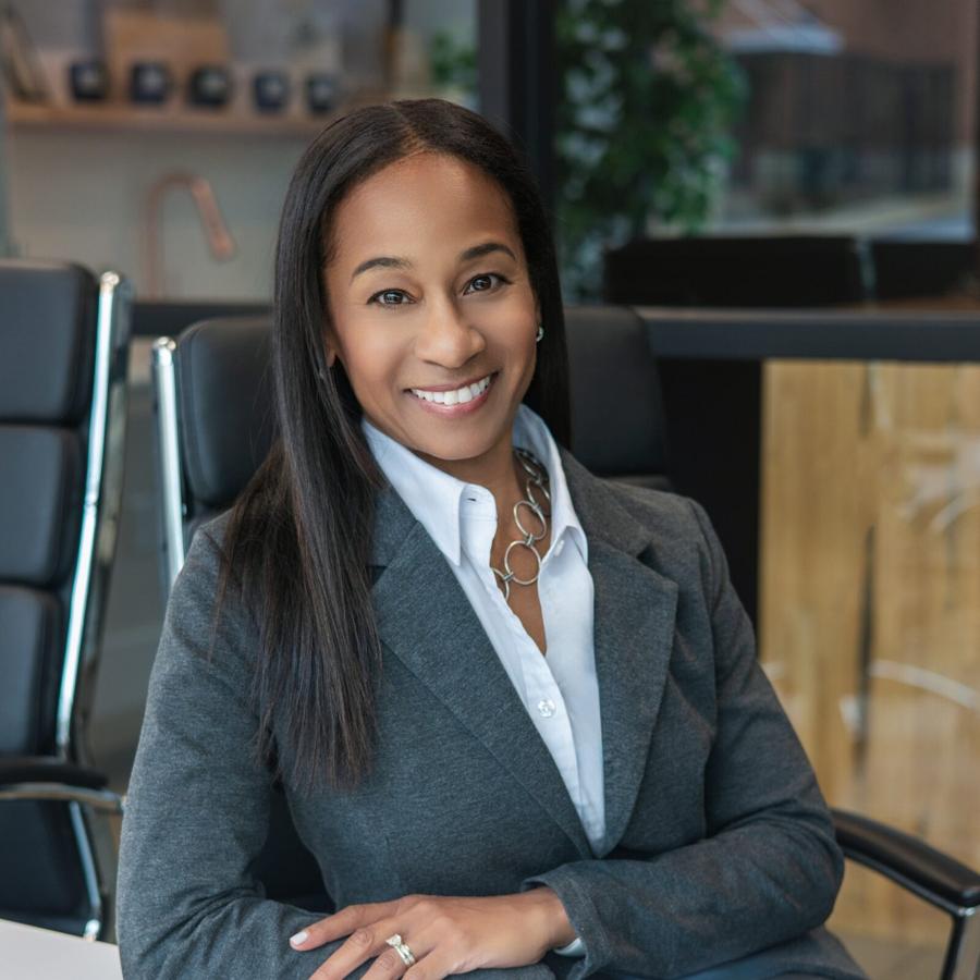 Executive headshot of a woman in a grey suit seated in a modern office