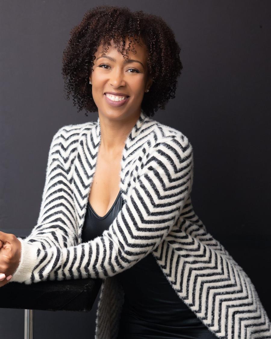 Studio headshot of a smiling woman in a striped cardigan against a dark backdrop