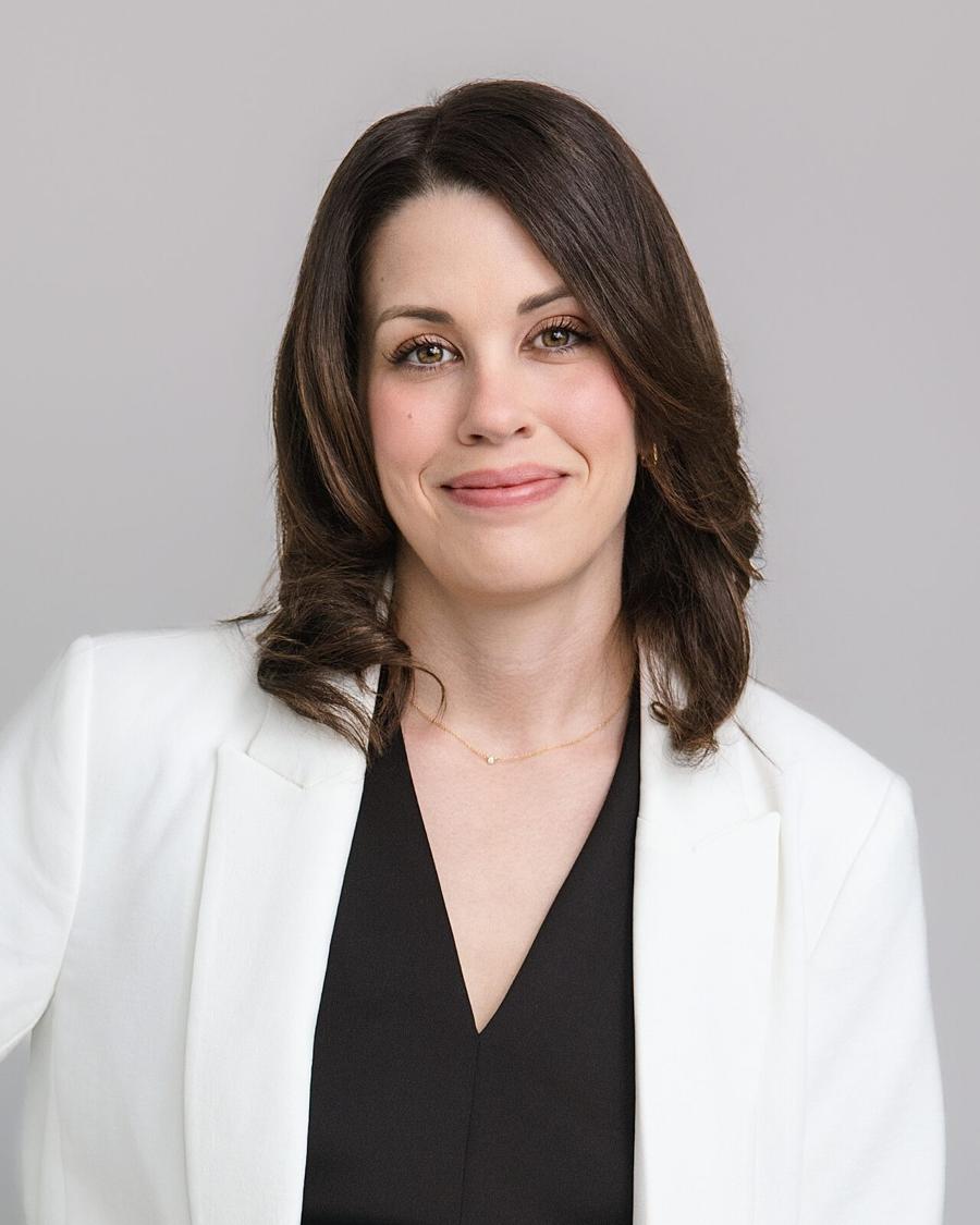 Business headshot of a woman in a white blazer against a light grey backdrop