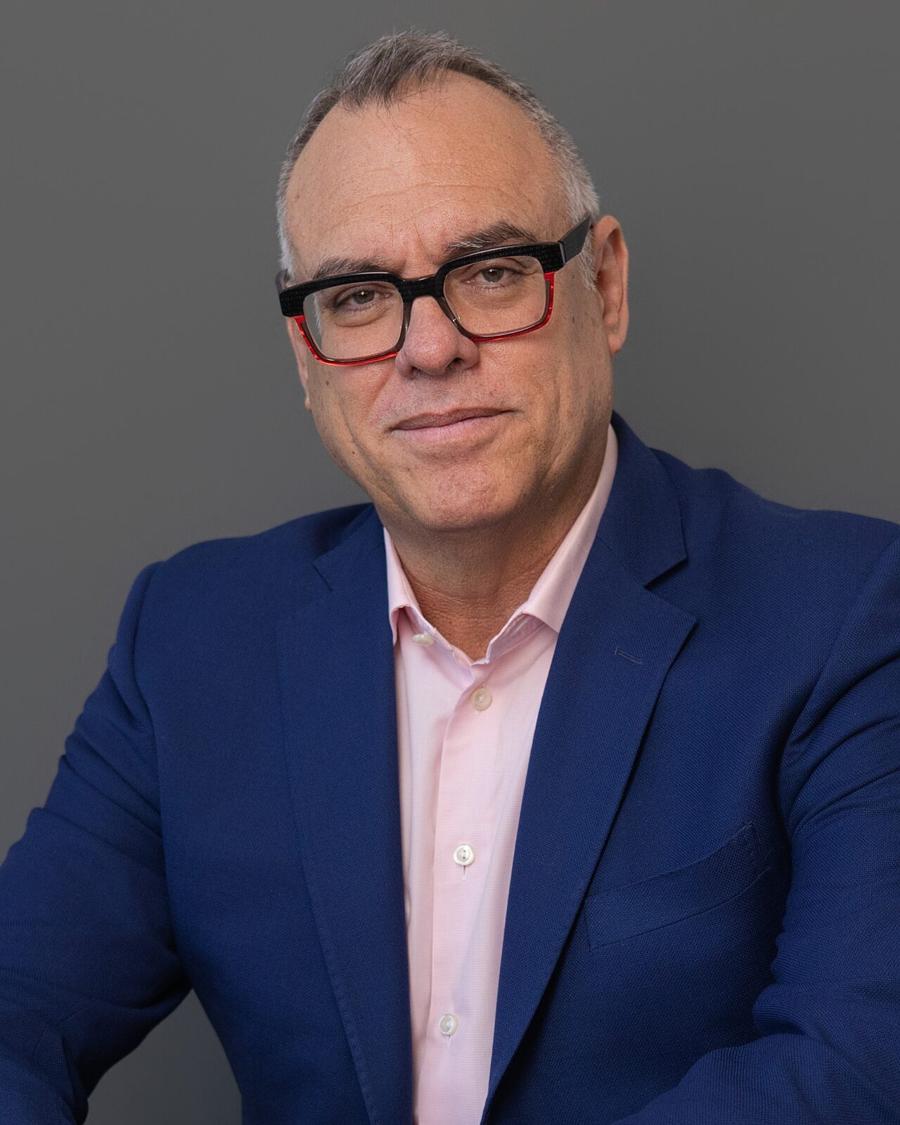 Corporate headshot of a man in a navy blazer and glasses