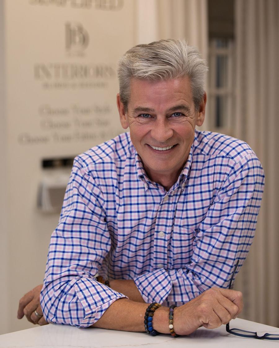 On-location business headshot of a smiling man in a plaid shirt at his showroom counter