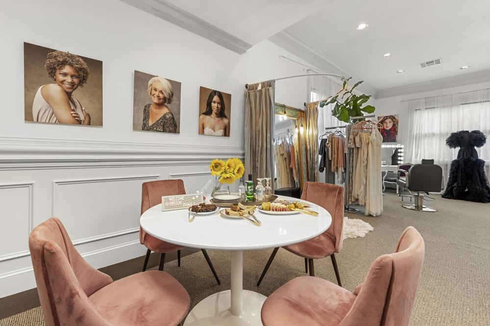 Dining corner with blush velvet chairs, a round table and studio portraits on the wall