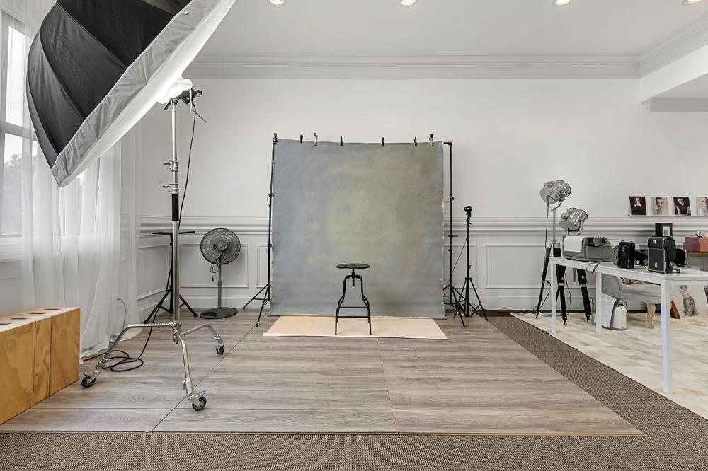 Portrait shooting area with a painted grey backdrop, stool and studio lights