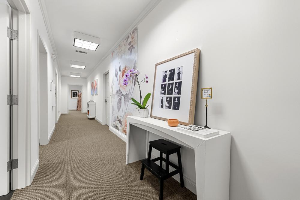 Hallway with an orchid, a framed portrait collage and a floral wall mural