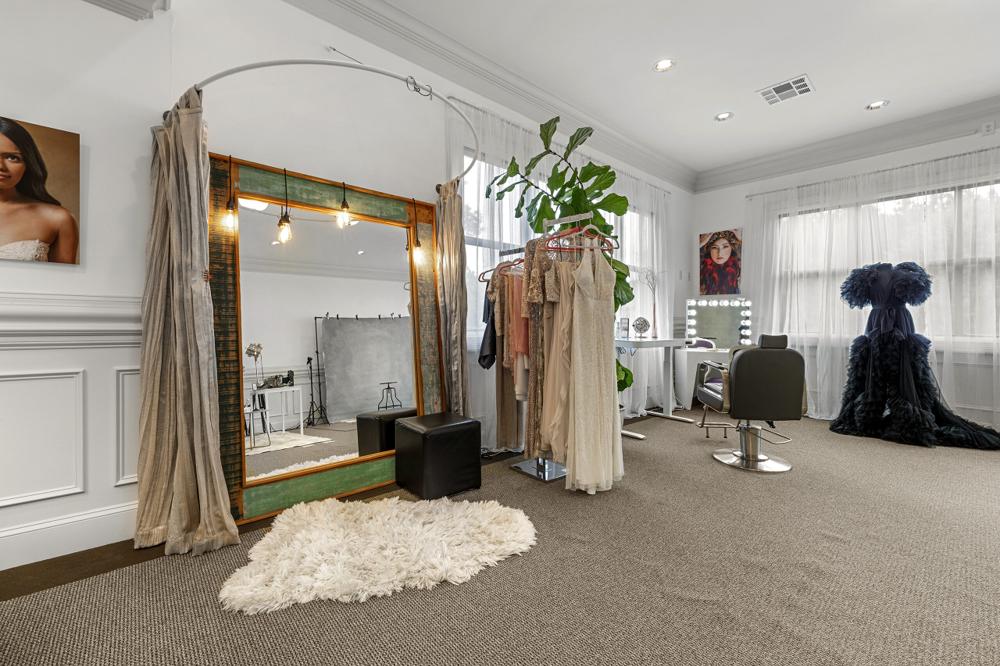 Full-length vintage mirror with gowns on the rack and a sheepskin rug