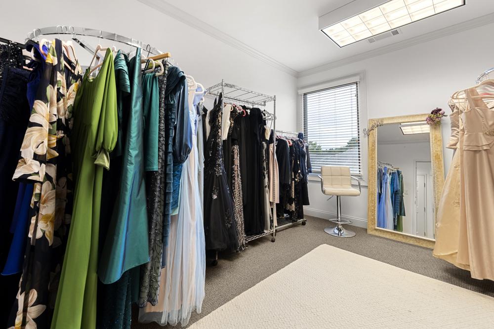Racks of patterned, green, teal and black dresses in the wardrobe room
