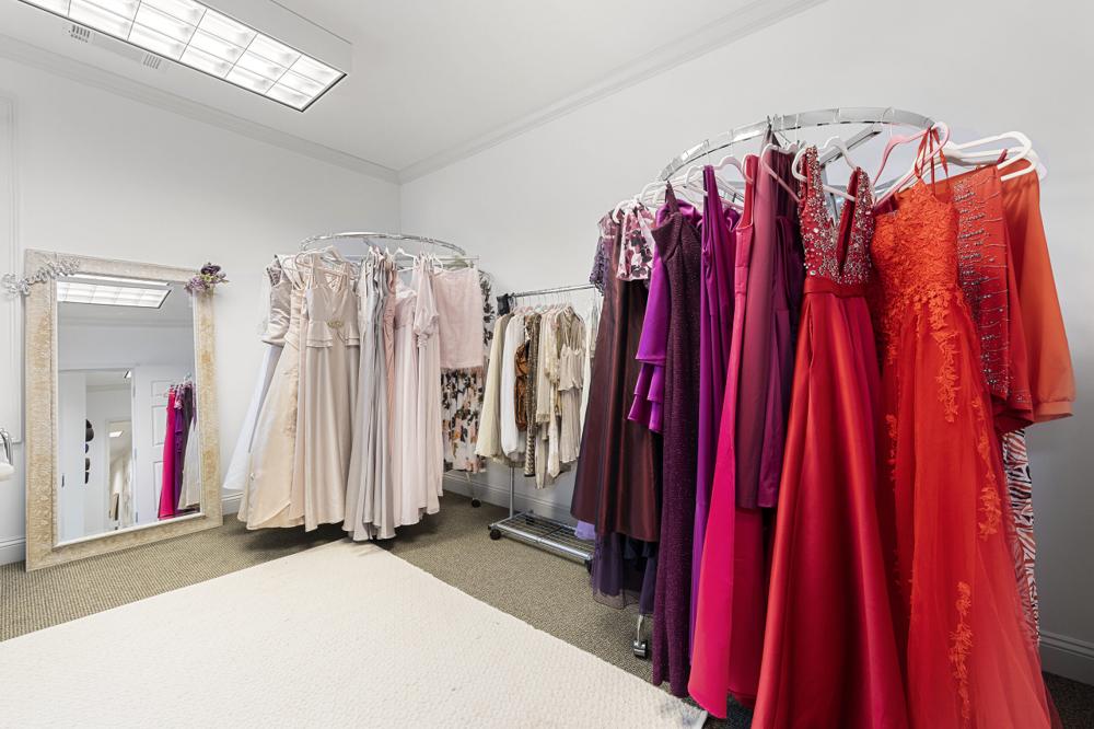 Studio closet with racks of red, purple and neutral gowns and a full-length mirror