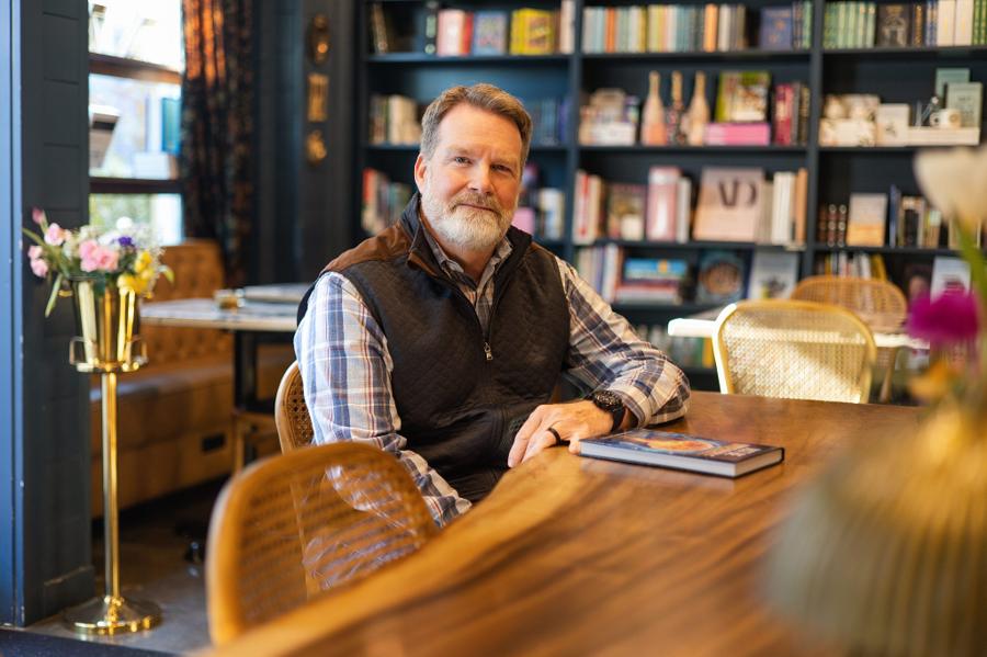 Personal branding photo of a bearded author seated at a wooden table in a bookshop café