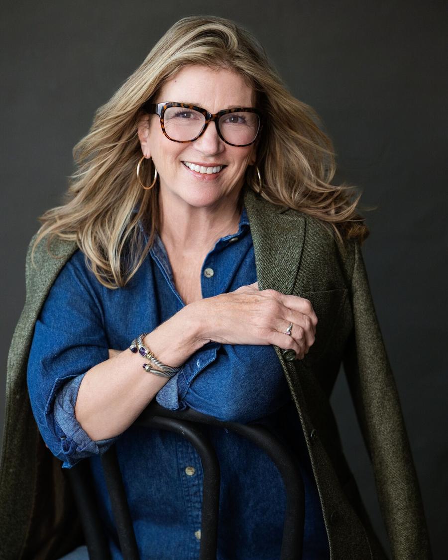Professional headshot of a woman in glasses, a denim shirt and an olive jacket