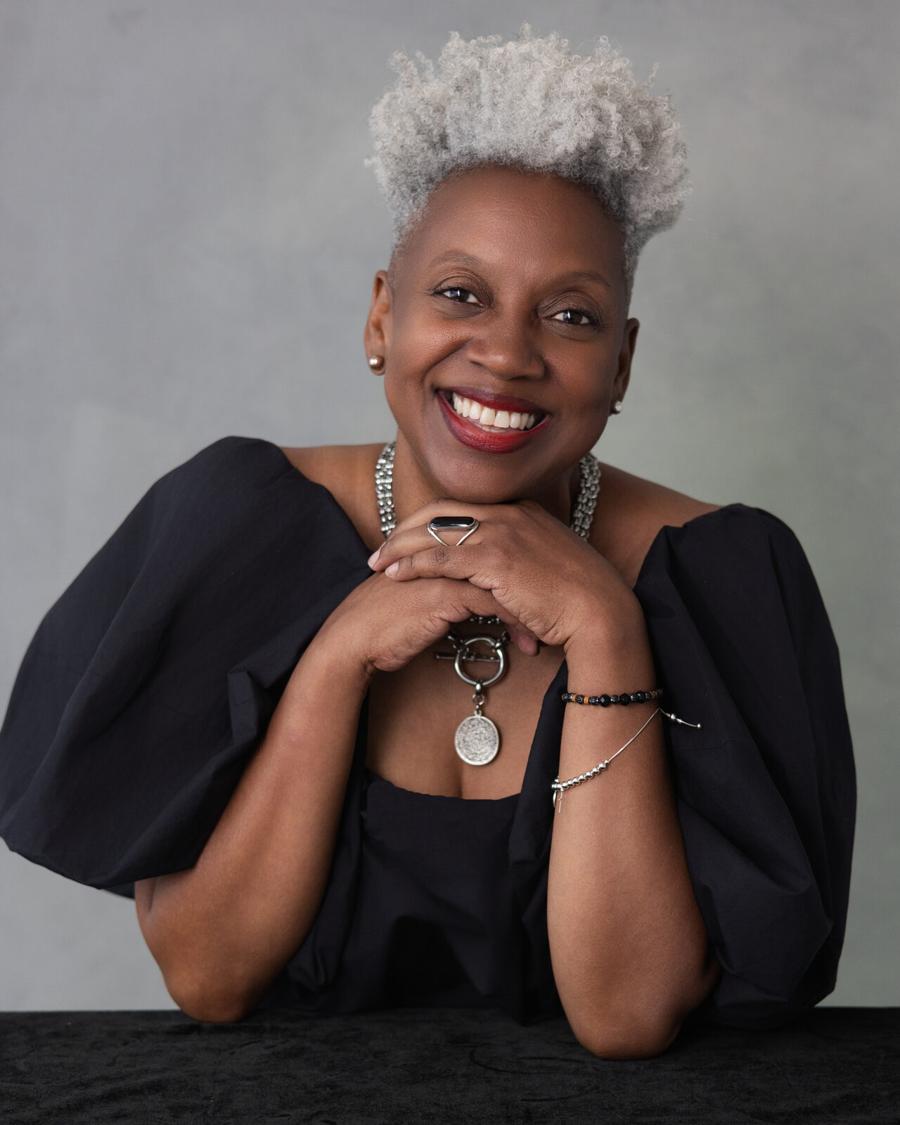 Studio portrait of a smiling woman with silver hair in a black off-the-shoulder top